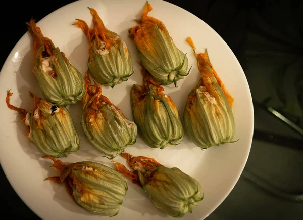 Koyu arkaplanda beyaz bir tabakta doldurulmuş kabak çiçekleri resmi, geleneksel İtalyan yemekleri (seçici odak))