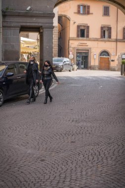 Viterbo, İtalya - 23 Şubat 2021, Viterbo, İtalya 'da sokakta siyah cübbeli ve siyah maskeli iki genç kadın