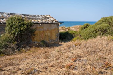İtalya 'nın Torre Astura kentindeki kum tepeleri arasında çökmüş çatısı olan eski bir evin kalıntıları.