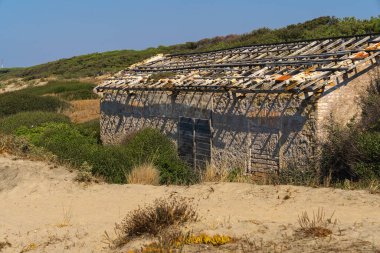 İtalya 'nın Torre Astura kentindeki kum tepeleri arasında çökmüş çatısı olan eski bir evin kalıntıları.