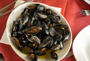 İtalya 'da kırmızı bir masa örtüsünde sotelenmiş midye resmi