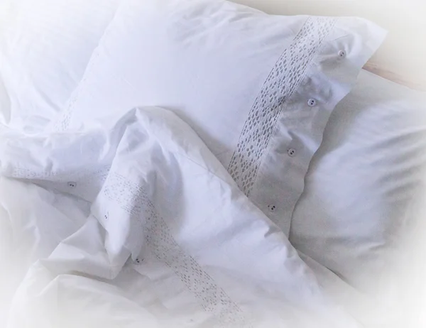 Lençóis brancos bordados, travesseiros e cobertor Imagens Royalty-Free