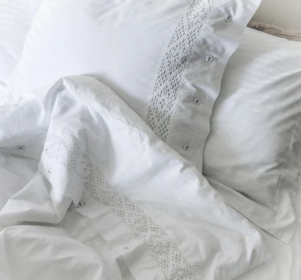 Lençóis brancos bordados, travesseiros e cobertor Imagem De Stock