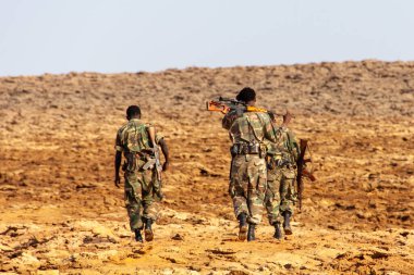 Dallol, Etiyopya - 17 Ocak 2014: Çölde yürüyen üç Etiyopyalı askerin arka planı