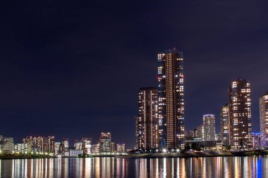 Su yüzeyine yansıyan yüksek katlı apartmanların gece görüşü