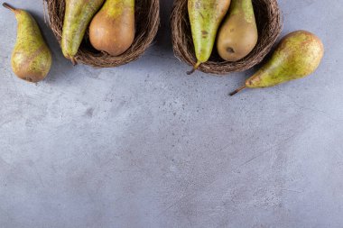 Gri arka planda hasır sepetlerde olgun armutlar