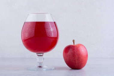 Bir bardak elma suyu ve mutfak masasında taze elma. 