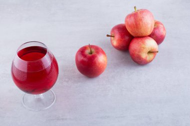 Gri arkaplanda bir bardak elma suyu ve elma.