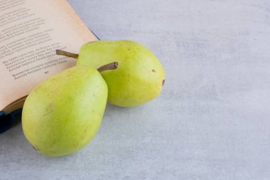Taze armutlar ve mutfak masasında kitap. Metin için boş alan.