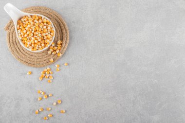 Gri arka planda bir kasedeki çiğ mısır tohumları. Üst Manzara. Boşluğu kopyala.
