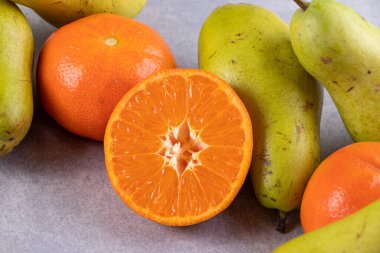 Gri bir zemin üzerinde taze armutlar ve mandalinalar. 