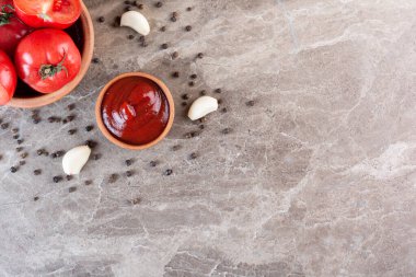 Baharatlı domates sosu ve gri arka planda çiğ domates. en üstteki görünüm.