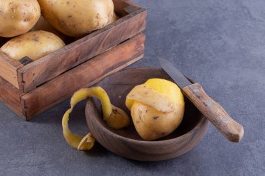 Gri arka planda tahta bir kutuda taze patatesler