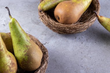 Gri bir arka planda sepetlerde taze armutlar..