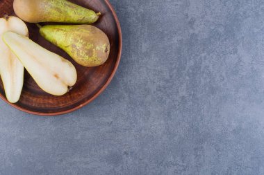 Olgun yeşil armutlar gri bir zemin üzerinde kil plaka. 