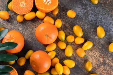 Gri bir zemin üzerinde taze kumkatlar ve mandalinalar. 