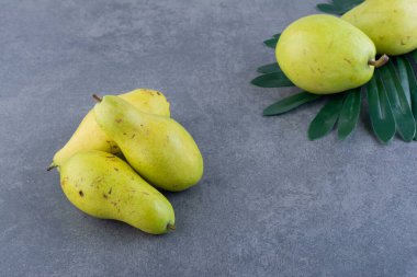 Taze yeşil armutlar ve gri arka planda yeşil yaprak