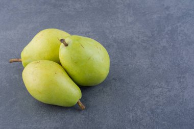 Gri arka planda olgun yeşil armutlar. 