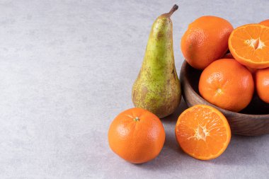 Gri bir zemin üzerinde taze armutlar ve mandalinalar. 