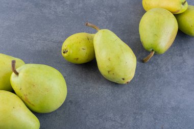 Gri arka planda olgun yeşil armutlar. 