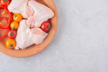 Çiğ tavuk bacağı ve sebze tabağı.