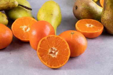 Gri bir zemin üzerinde taze armutlar ve mandalinalar. 