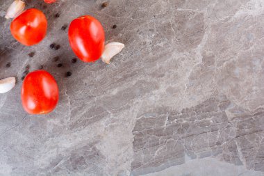 Gri arkaplanda taze domates ve sarımsak karanfilleri