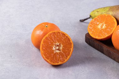 Gri bir zemin üzerinde taze armutlar ve mandalinalar. 