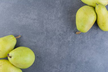 Gri arka planda olgun yeşil armutlar. 