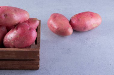 Gri arka planda sepetteki taze kırmızı patatesler.