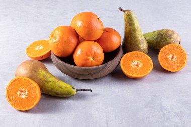 Gri bir zemin üzerinde taze armutlar ve mandalinalar. 