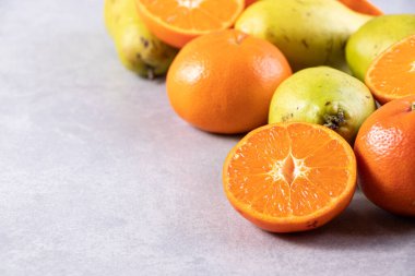 Gri bir zemin üzerinde taze armutlar ve mandalinalar. 