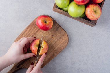Kadın mutfak masasında taze elma kesiyor. Metin için boş alan.