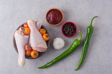 Gri masada baharatlı ve sebzeli çiğ tavuk. 