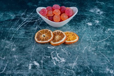 Koyu arkaplanda kurumuş portakal dilimleri ve adaylar..