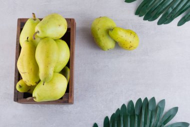 Taze olgun armutlar ve gri arka planda ahşap bir kutu.