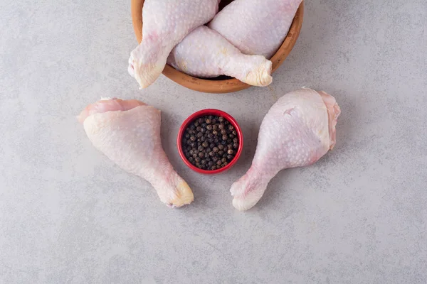 raw chicken legs with spices on a grey background