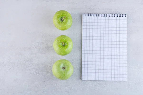 green apples and notepad on grey background