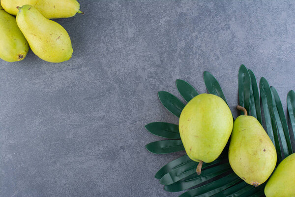 свежие зеленые груши и зеленый лист на сером фоне