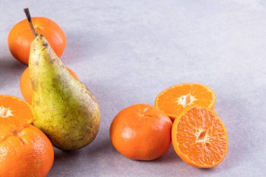 Gri bir zemin üzerinde taze armutlar ve mandalinalar. 