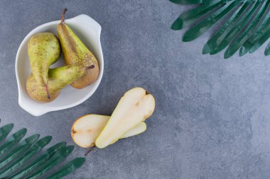 Olgun yeşil armutlar gri bir zemin üzerinde kil plaka. 