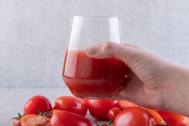 Elinde domates suyu ve taze domates var. 