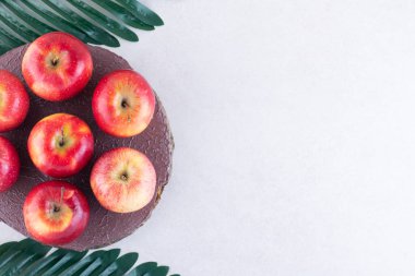 Gri arkaplanda taze kırmızı elmalar ve yeşil yapraklar 