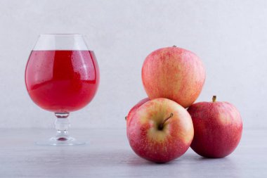 Gri arkaplanda bir bardak elma suyu ve elma.