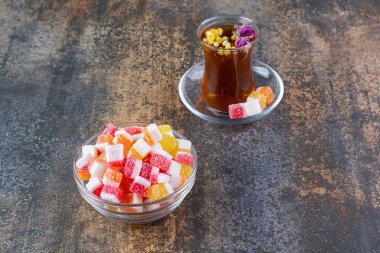 Renkli jöle şekerleri ve mavi arka planda bitki çayı.