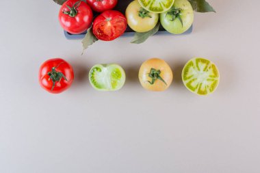 Gri mutfak masasında taze yeşil ve kırmızı domatesler