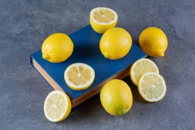 Taze limonlar ve gri arka planda bir kitap. en üstteki görünüm.