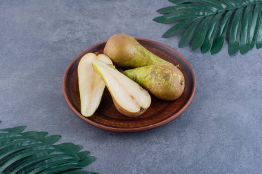 Olgun yeşil armutlar gri bir zemin üzerinde kil plaka. 