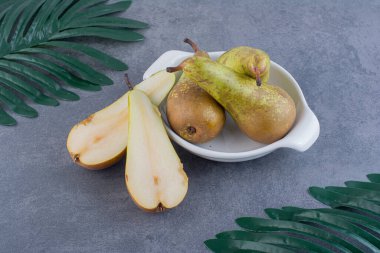 Olgun yeşil armutlar gri bir zemin üzerinde kil plaka. 