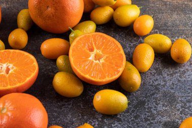 Gri bir zemin üzerinde taze kumkatlar ve mandalinalar. 